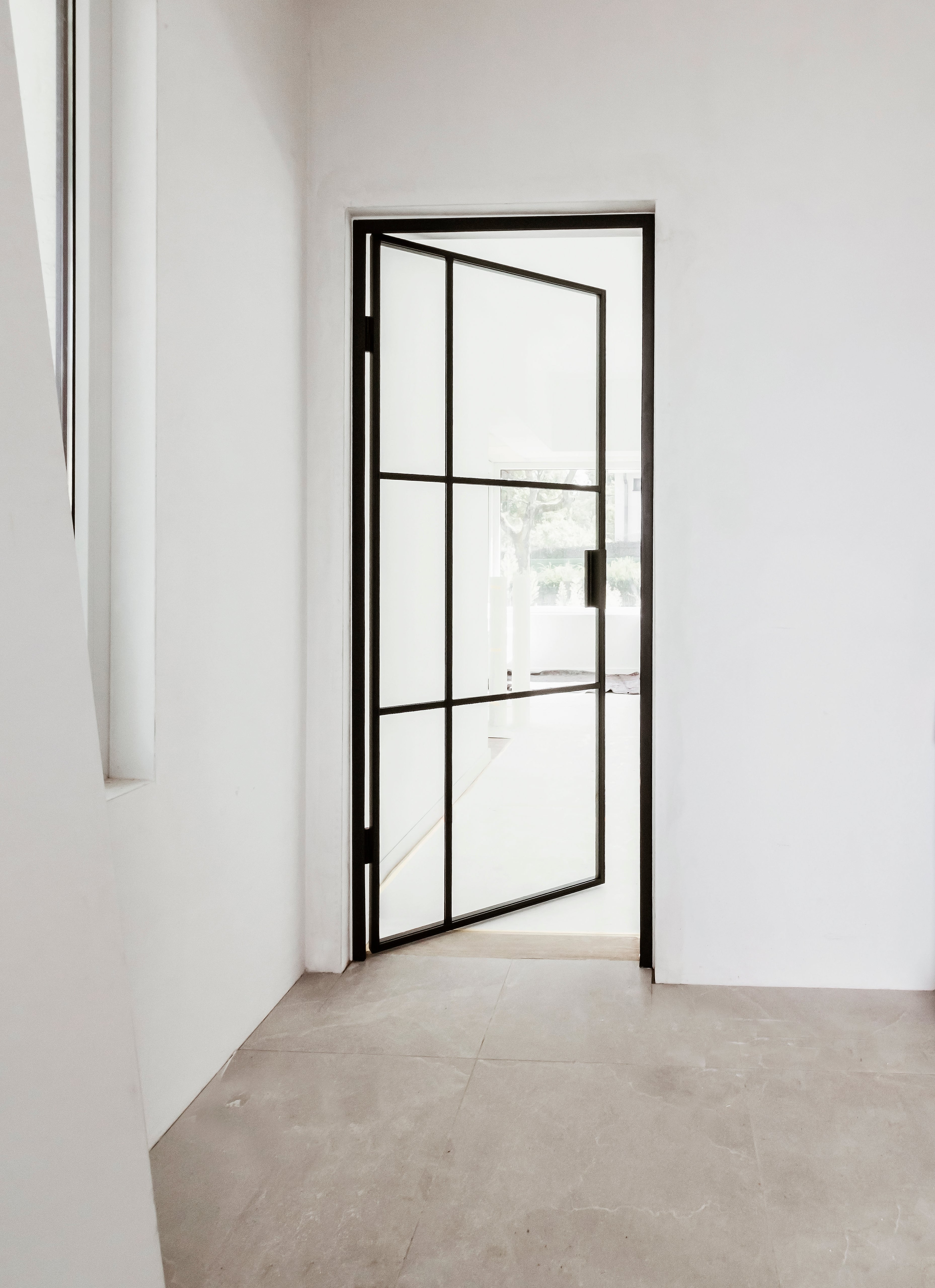 Modern interior with a black framed glass door in a white room.