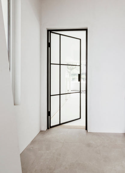 Modern interior with a black framed glass door in a white room.